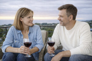 Ein Paar genießt ein Glas Wein auf einem Balkon bei Sonnenuntergang – Symbol für eine gemeinsame, kraftvolle Beziehungsvision und den Silberstreif am Horizont.